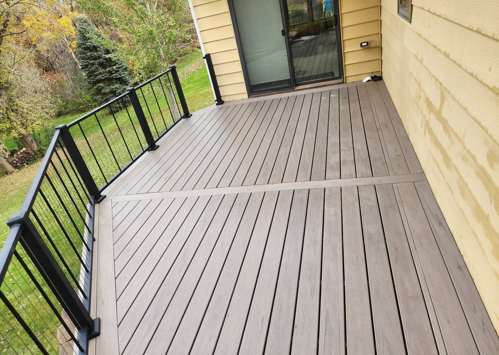 Composite deck with black aluminum railing, by New West Co
