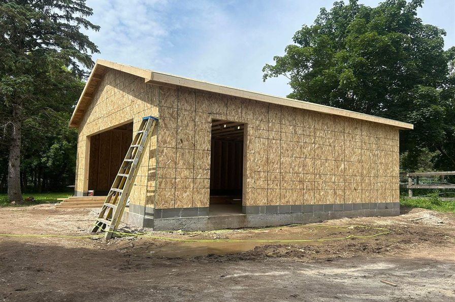 Detached garage sheathed and roofed, by New West Co