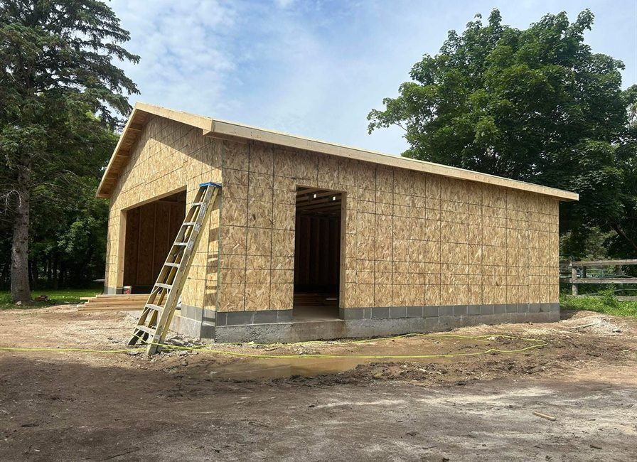 Detached garage sheathed and roofed, by New West Co